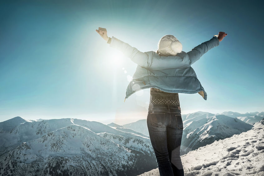 Woman expressing happiness on top of a snow capped mountain